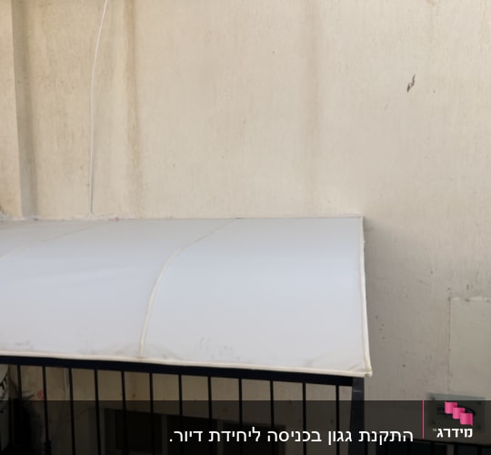 סוכך לבן מותקן על קיר חיצוני
